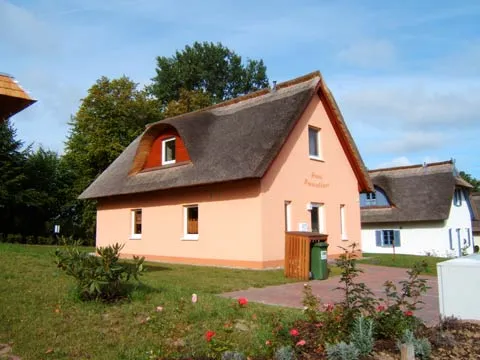 Seitenansicht des Ferienhauses mit blühendem Rosenbeet