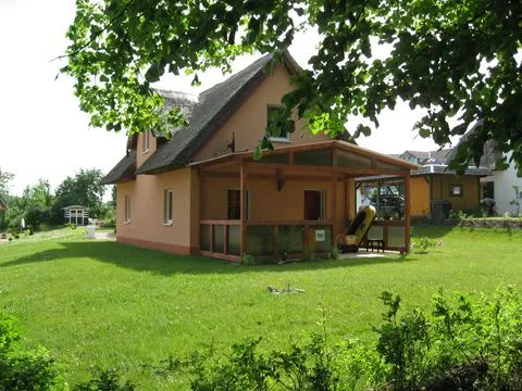 Reetdachhaus von der Gartenwiese aus, im Vordergrund ein Laubbaum