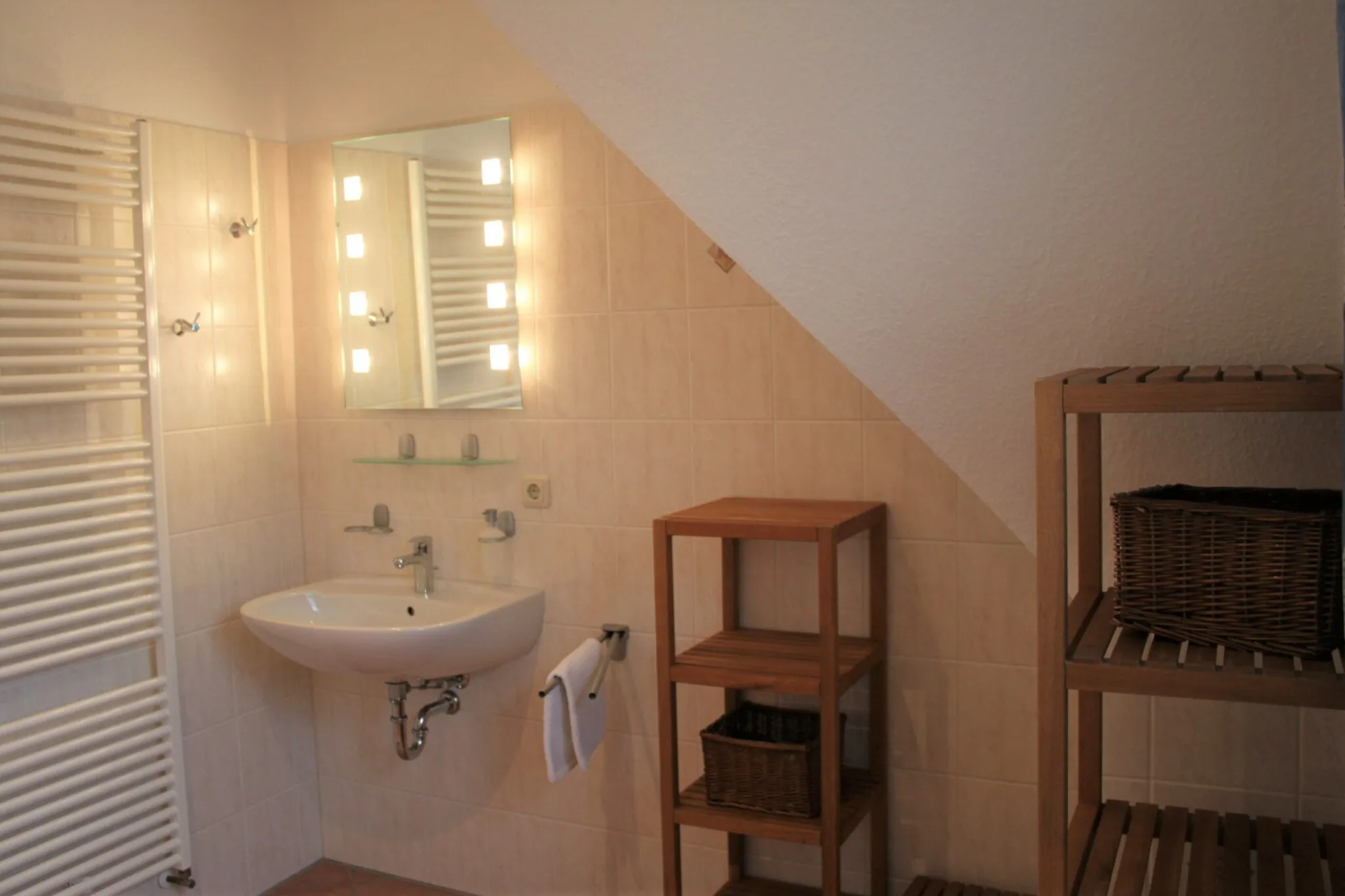 Badezimmer mit Waschbecken, Spiegel und Handtuchheizkörper