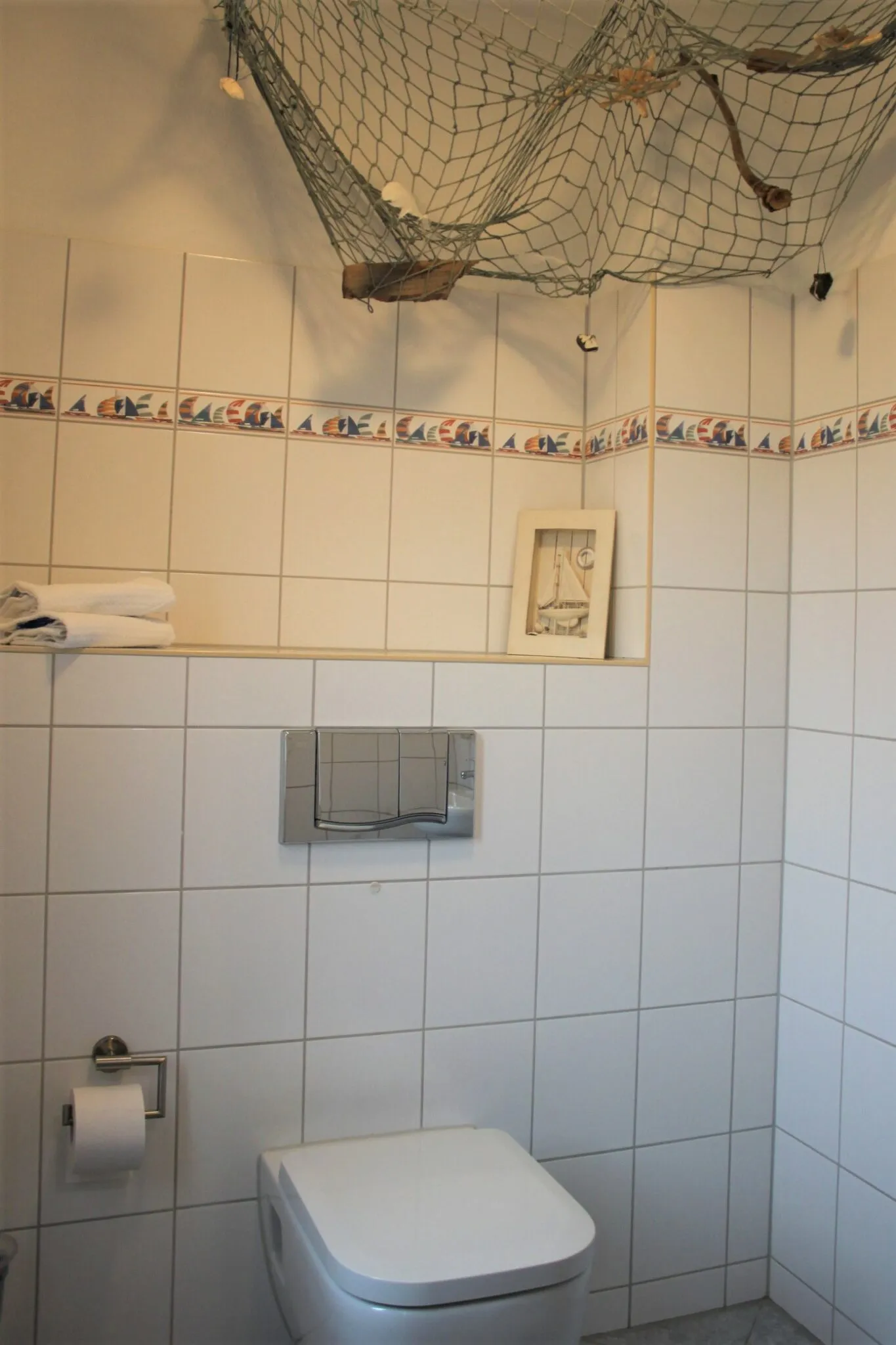 Gefliestes Gäste-WC mit Fischernetz als Wanddekoration