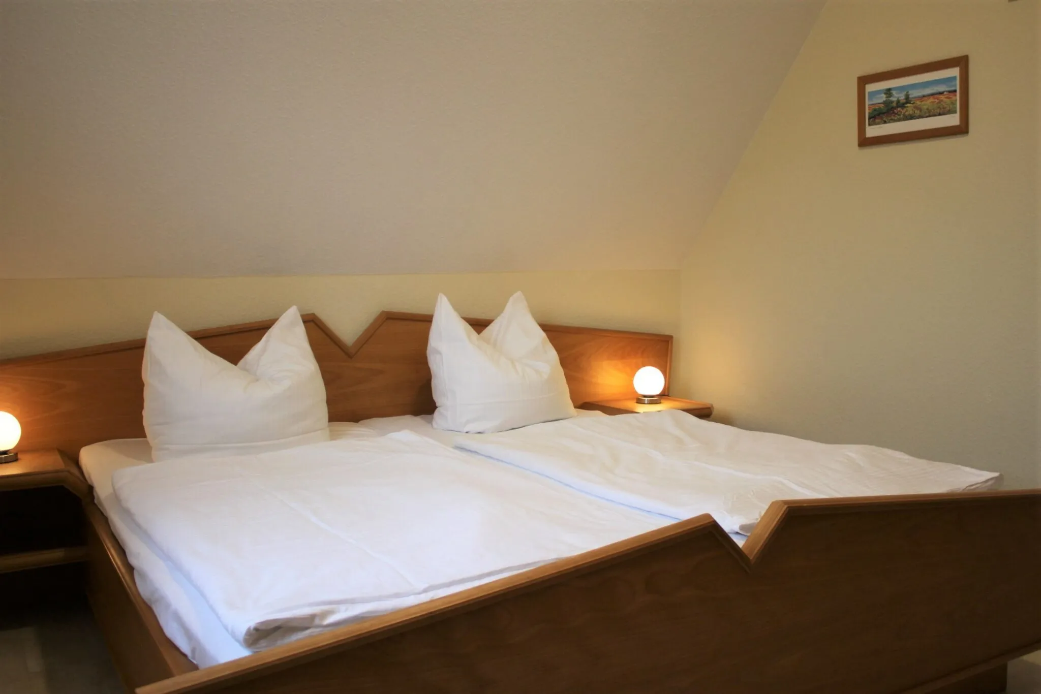 Schlafzimmer mit frisch bezogenem Doppelbett und Nachttischleuchte
