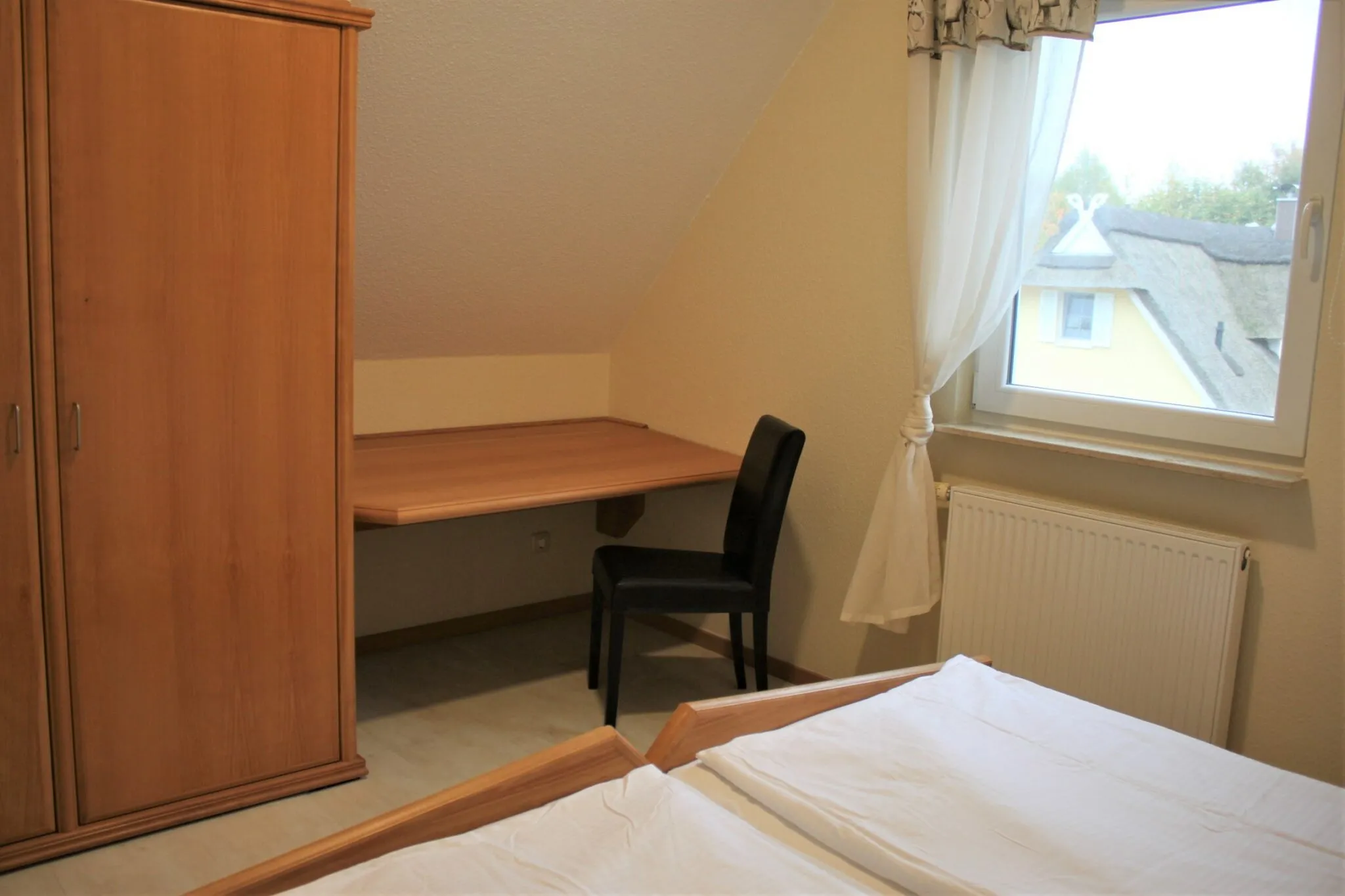 Schlafzimmer unter der Dachschräge mit Kleiderschrank und Schreibtisch